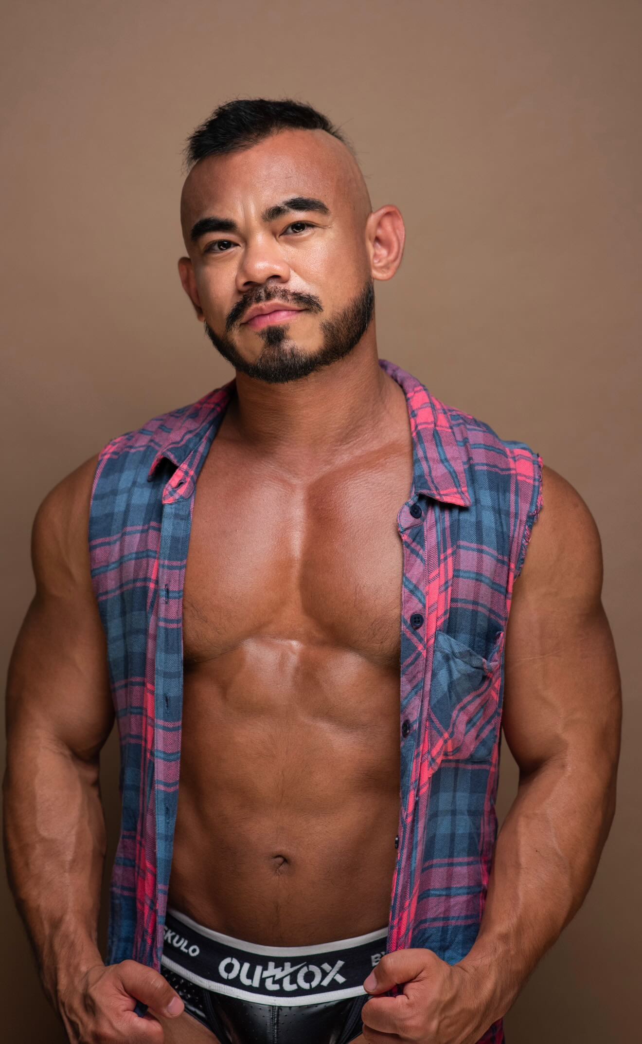 Jason Luna looks serious with a beard, eyebrow slit and plaid vest