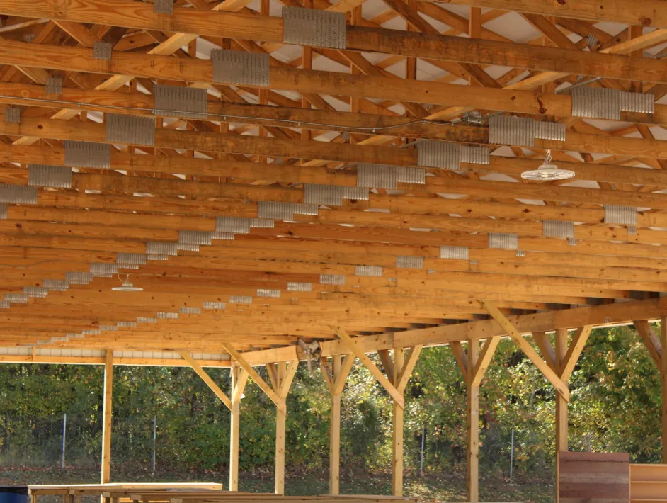 Wooden pavilion roof structure with multiple exposed beams and support columns outdoors.