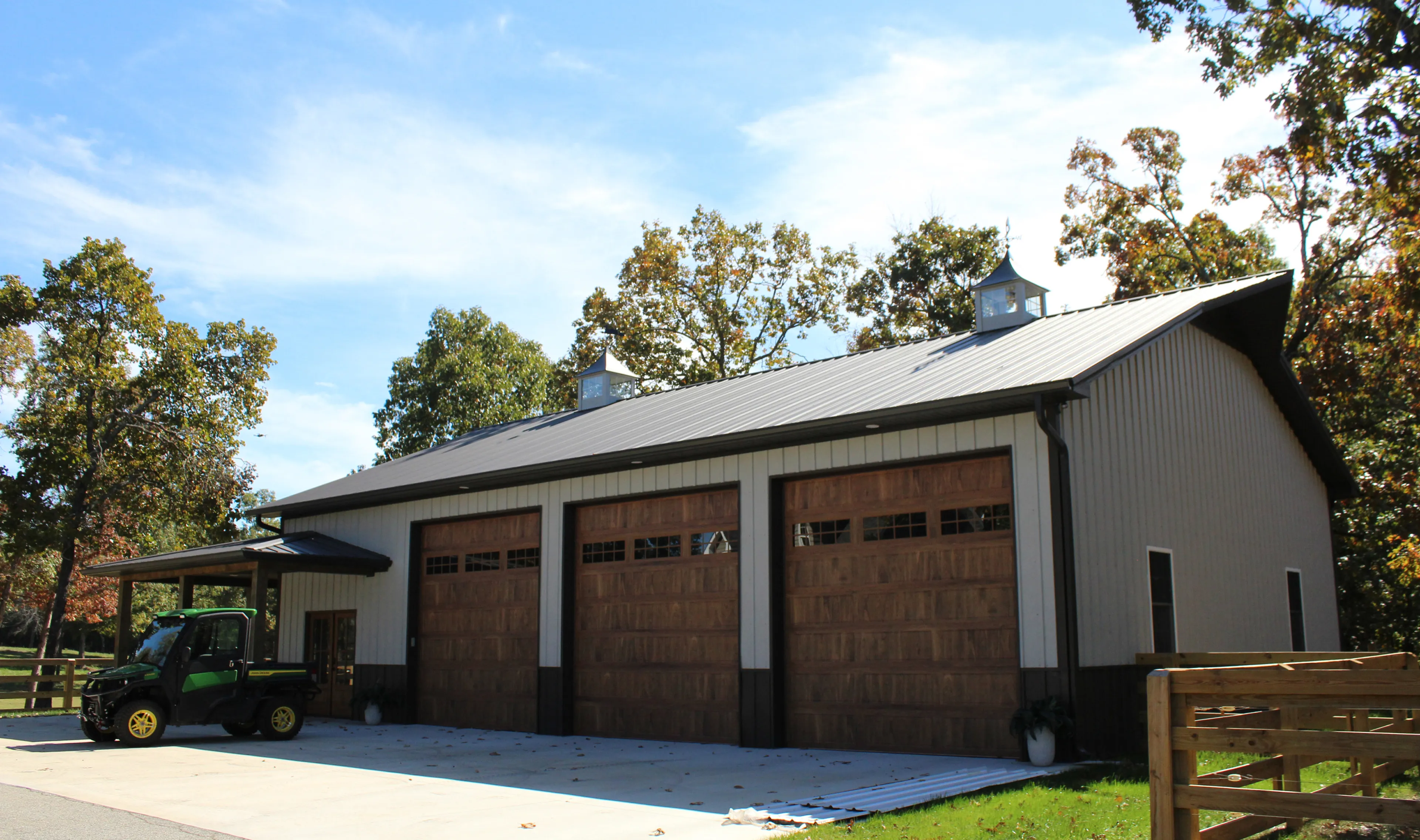 Barn with three closed wooden garage doors and an ATV parked in front.