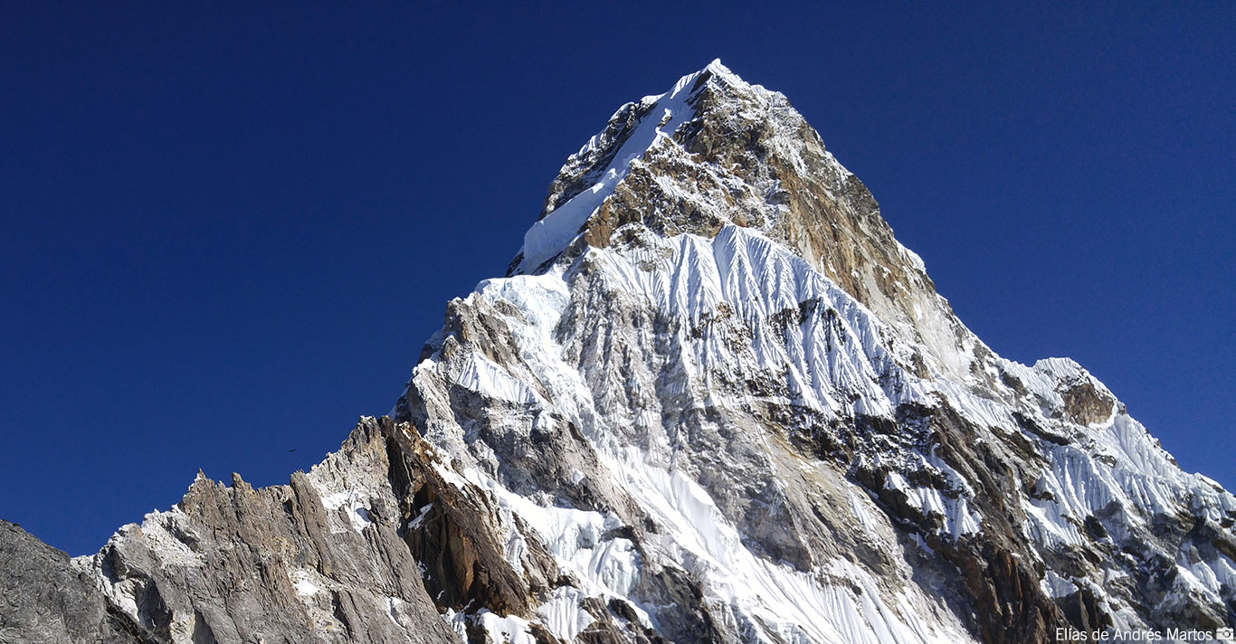 Snow-capped rocky mountain peak under a clear deep blue sky.