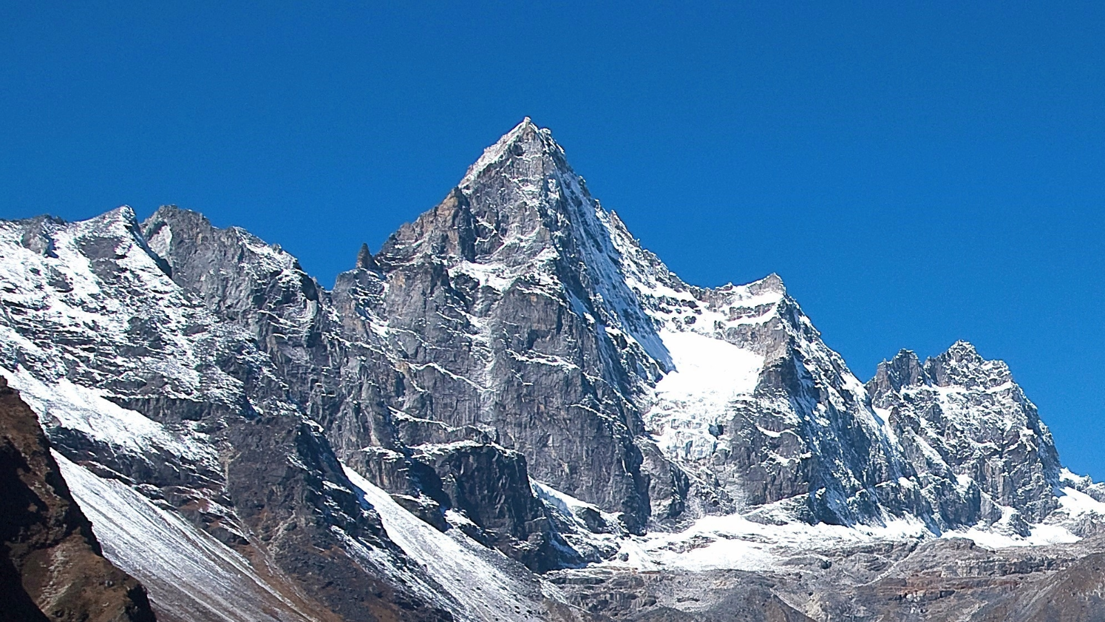 Sharp mountain peak with snow patches under a clear blue sky.