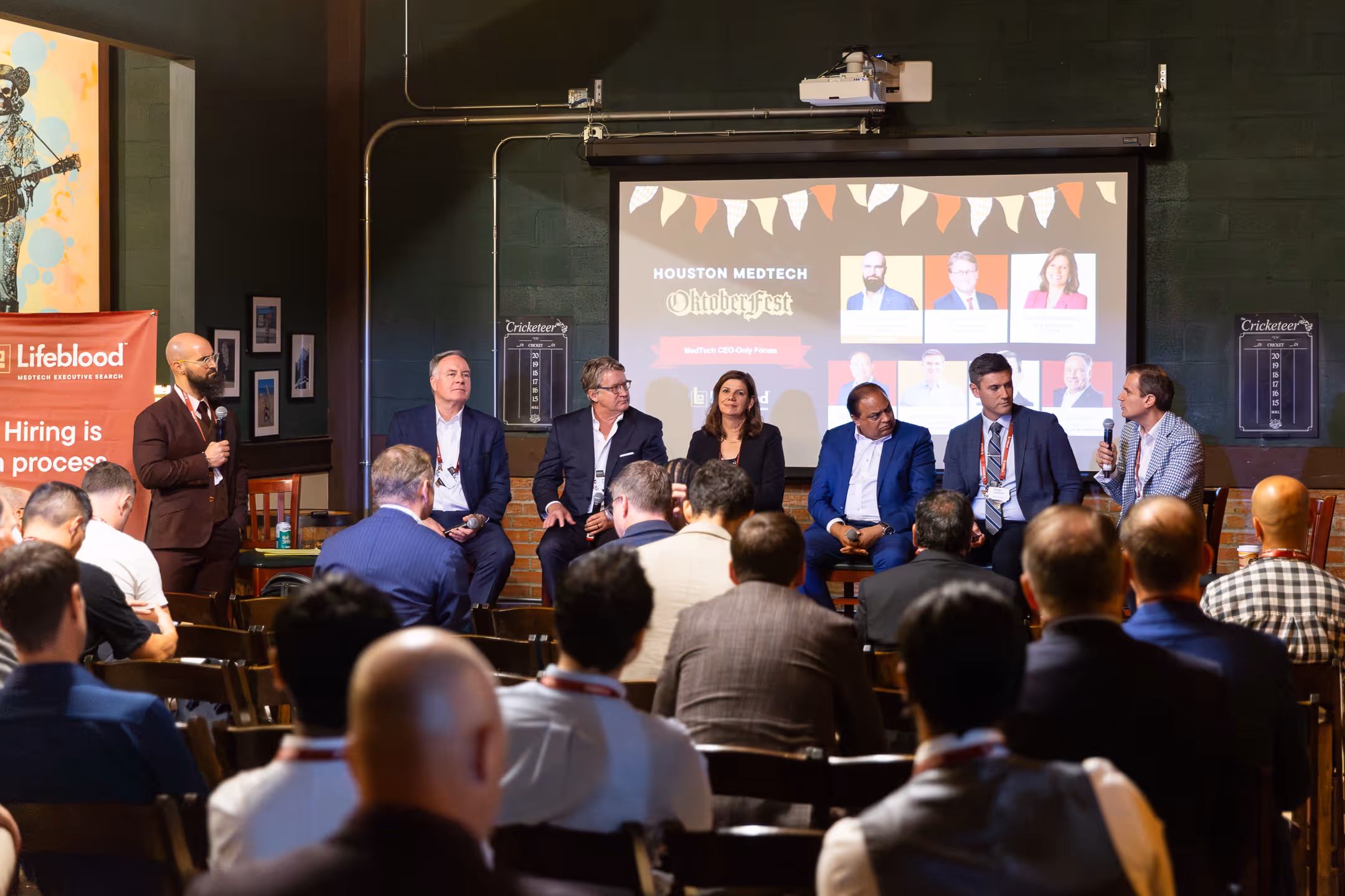 Panel discussion at Houston MedTech Oktoberfest with six speakers and an audience.