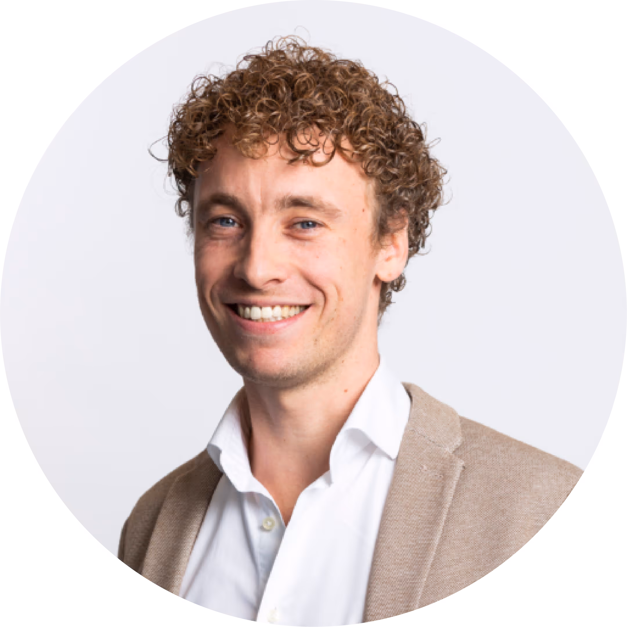 Smiling man with curly hair wearing a white shirt and beige blazer on a white background.
