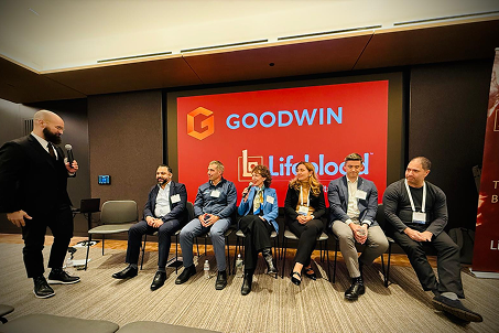 Group of people at an event, some wearing badges and holding drinks, engaged in conversation.