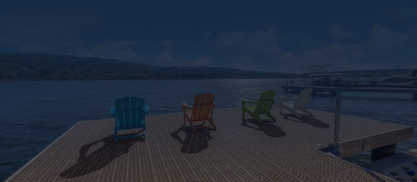 Modern dining area with a white table, four gray chairs, a staircase with metal railing, and large window overlooking greenery.