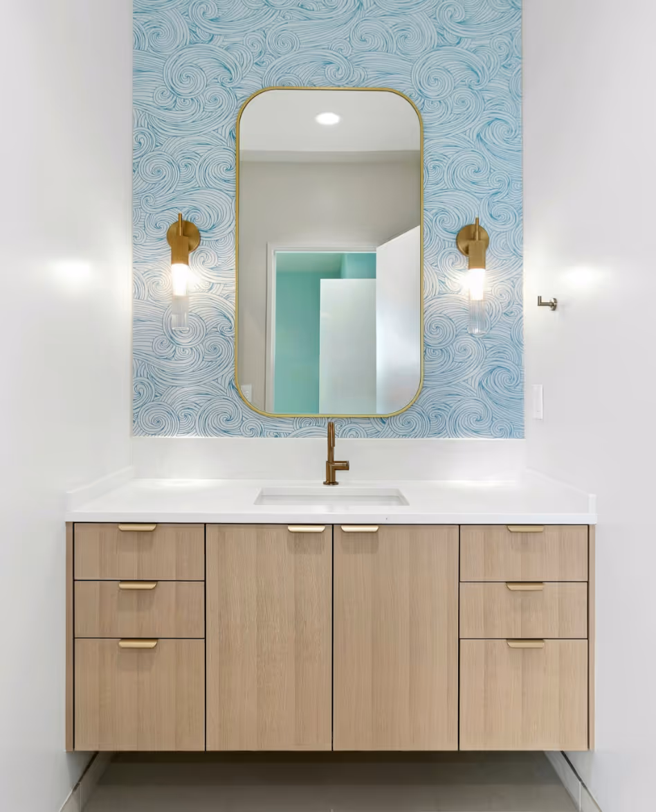 Modern two-story house exterior with concrete driveway, wooden front door, two black chairs with yellow cushions on the porch, and green lawn.