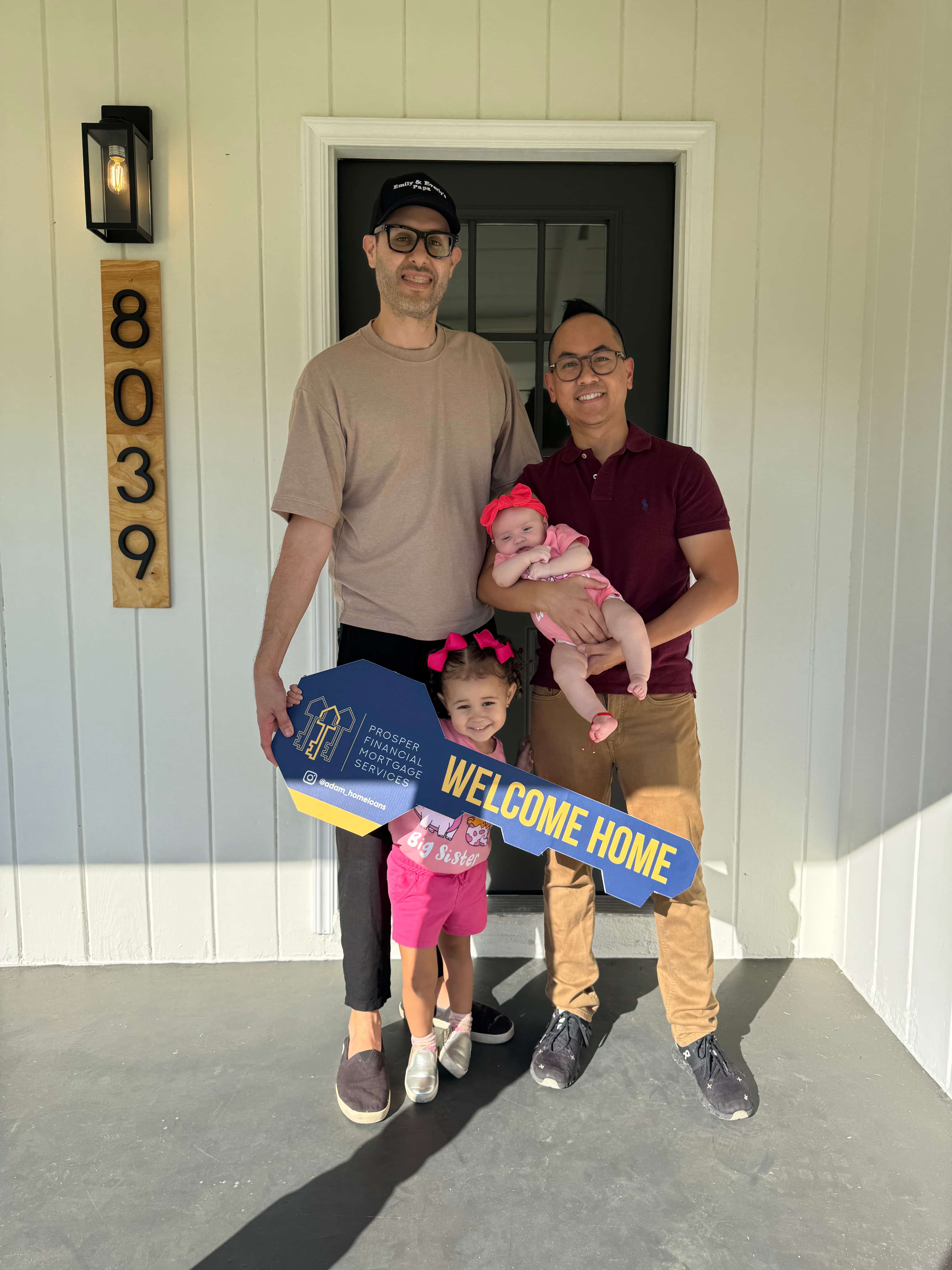 Two people indoors holding and swinging bright pink foam batons playfully on a wood floor with white walls and exposed wooden ceiling beam.