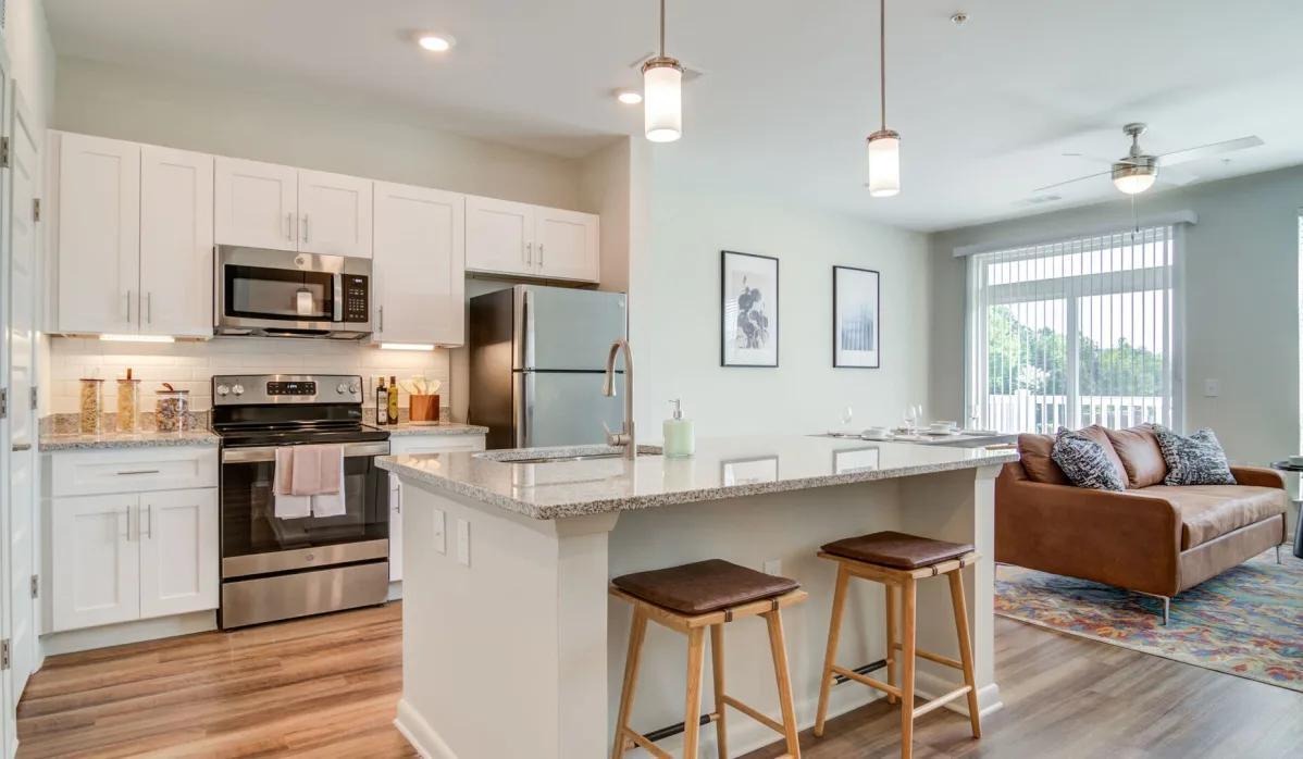 A modern kitchen with stainless steel appliances and a cozy couch in the apartment interior at Lofts at Hamilton.
