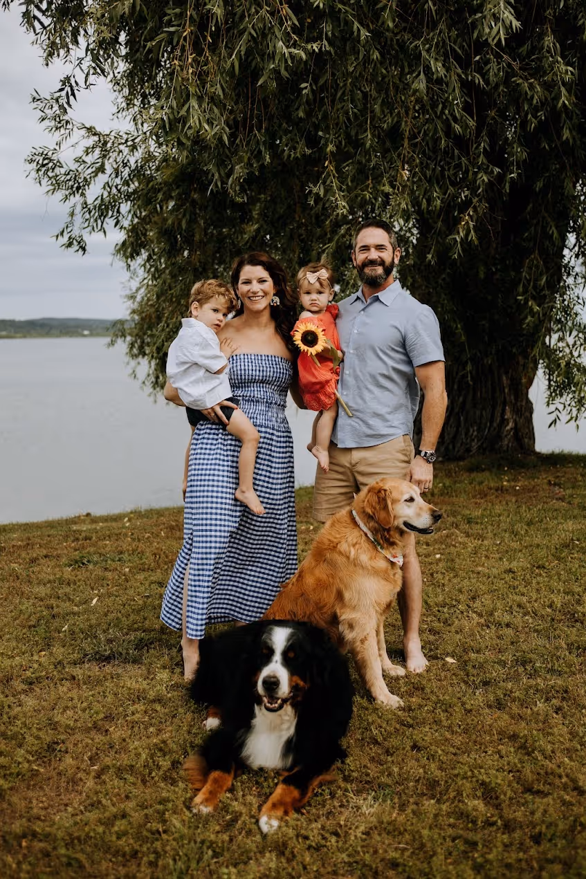 A man, woman, and two children posing for a picture with a dog.