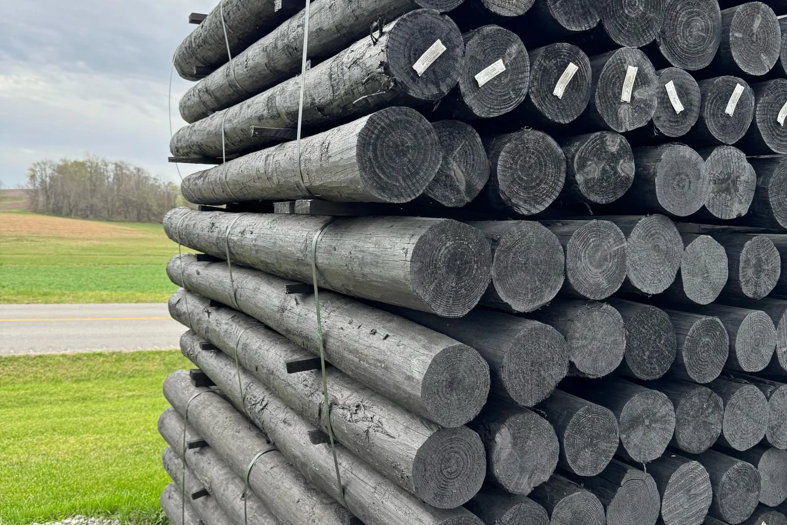 Pressure-treated fence posts stacked at a wholesale lumber supplier yard in Michigan