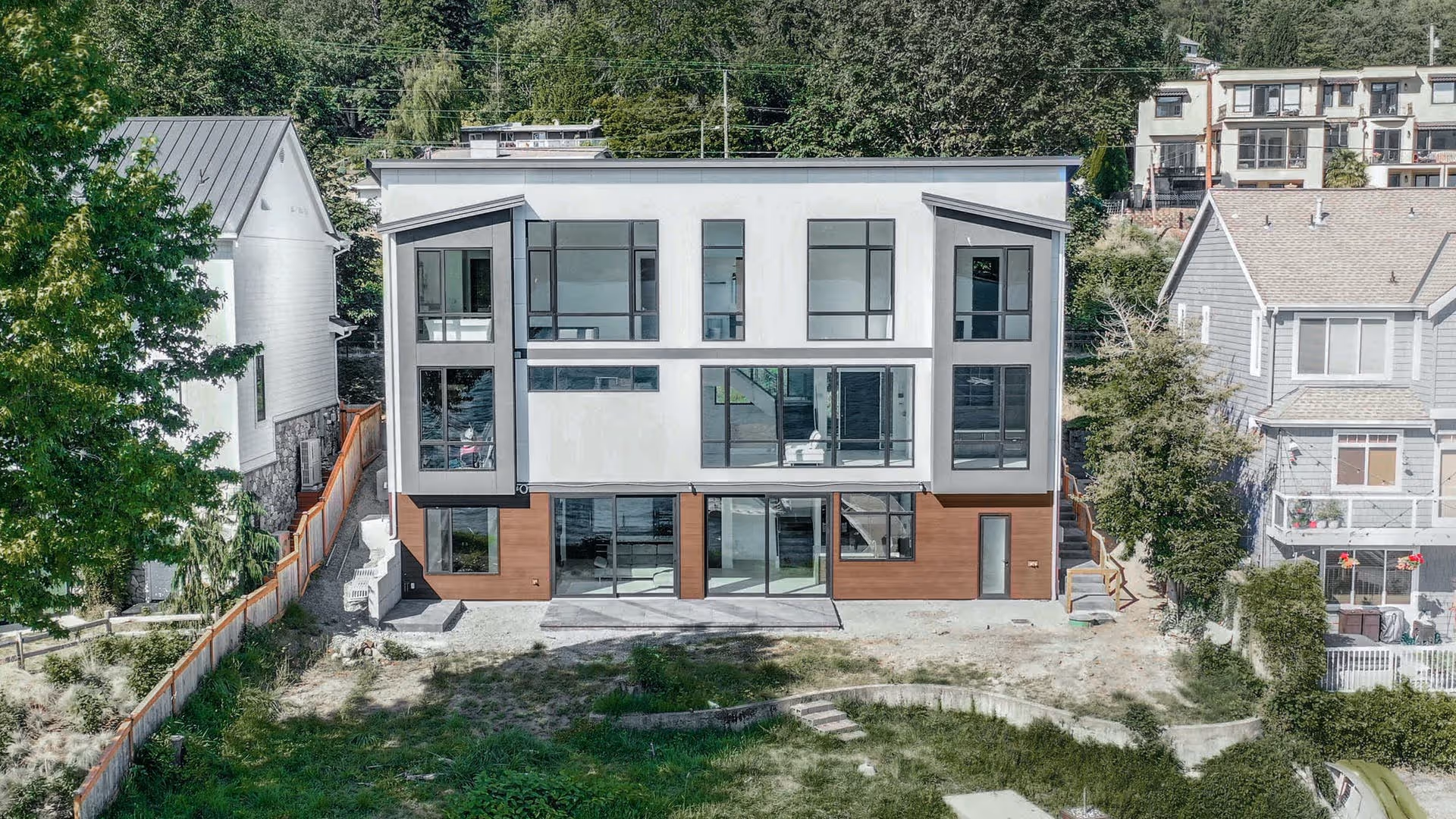 Modern open-concept living room and kitchen with light wood cabinetry, white sofa, bar stools, and a large green landscape painting.