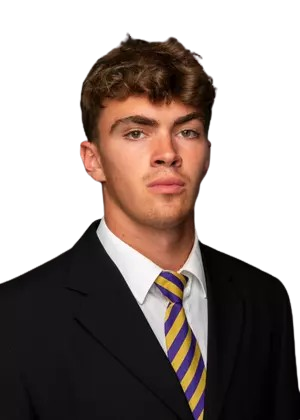 Young man with curly brown hair wearing a black suit, white shirt, and purple and yellow striped tie.