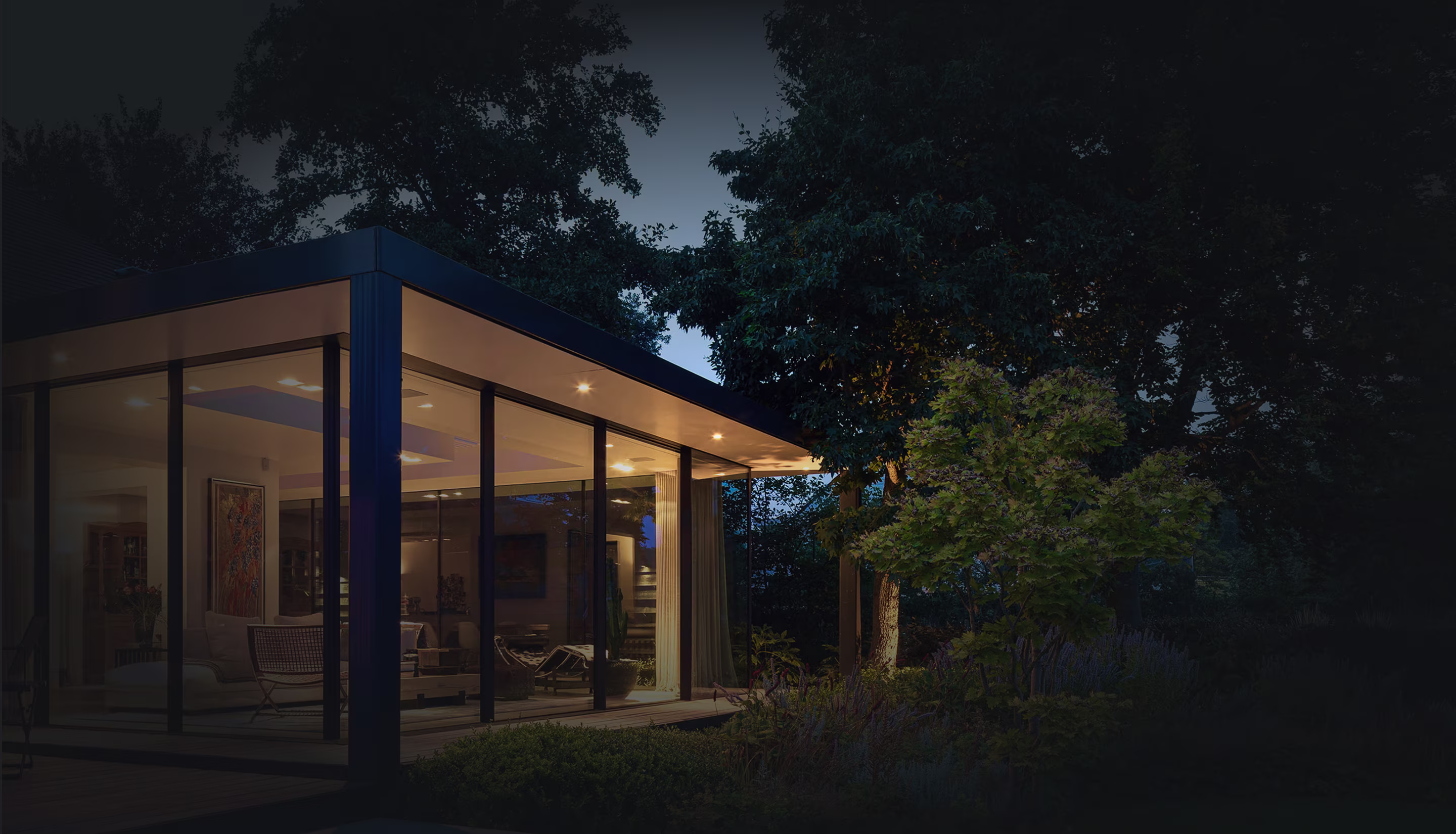 Modern glass-walled house lit warmly at dusk