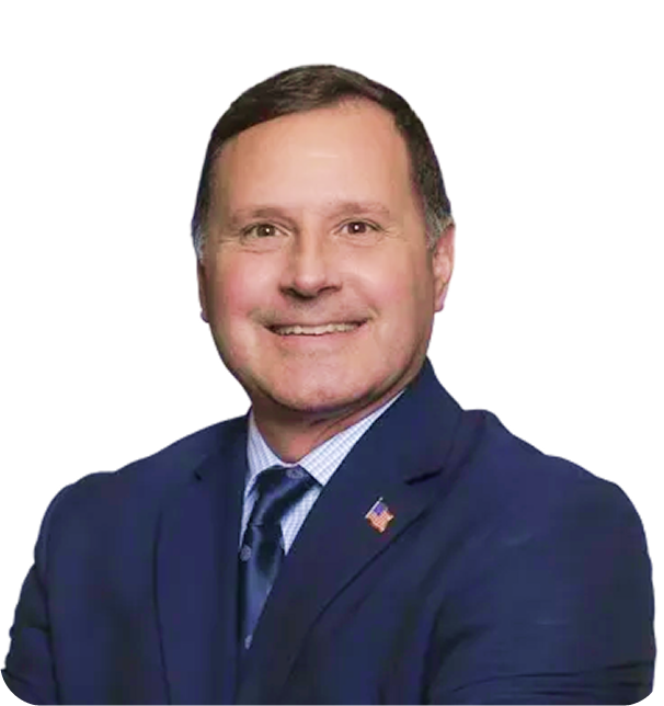 Smiling man in dark blue suit with American flag lapel pin on his jacket.
