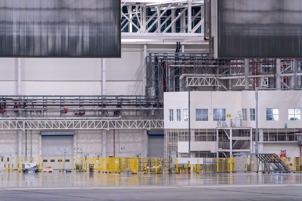 Interior of a large manufacturing facility with structural steelwork, mezzanine offices and marked floor lanes