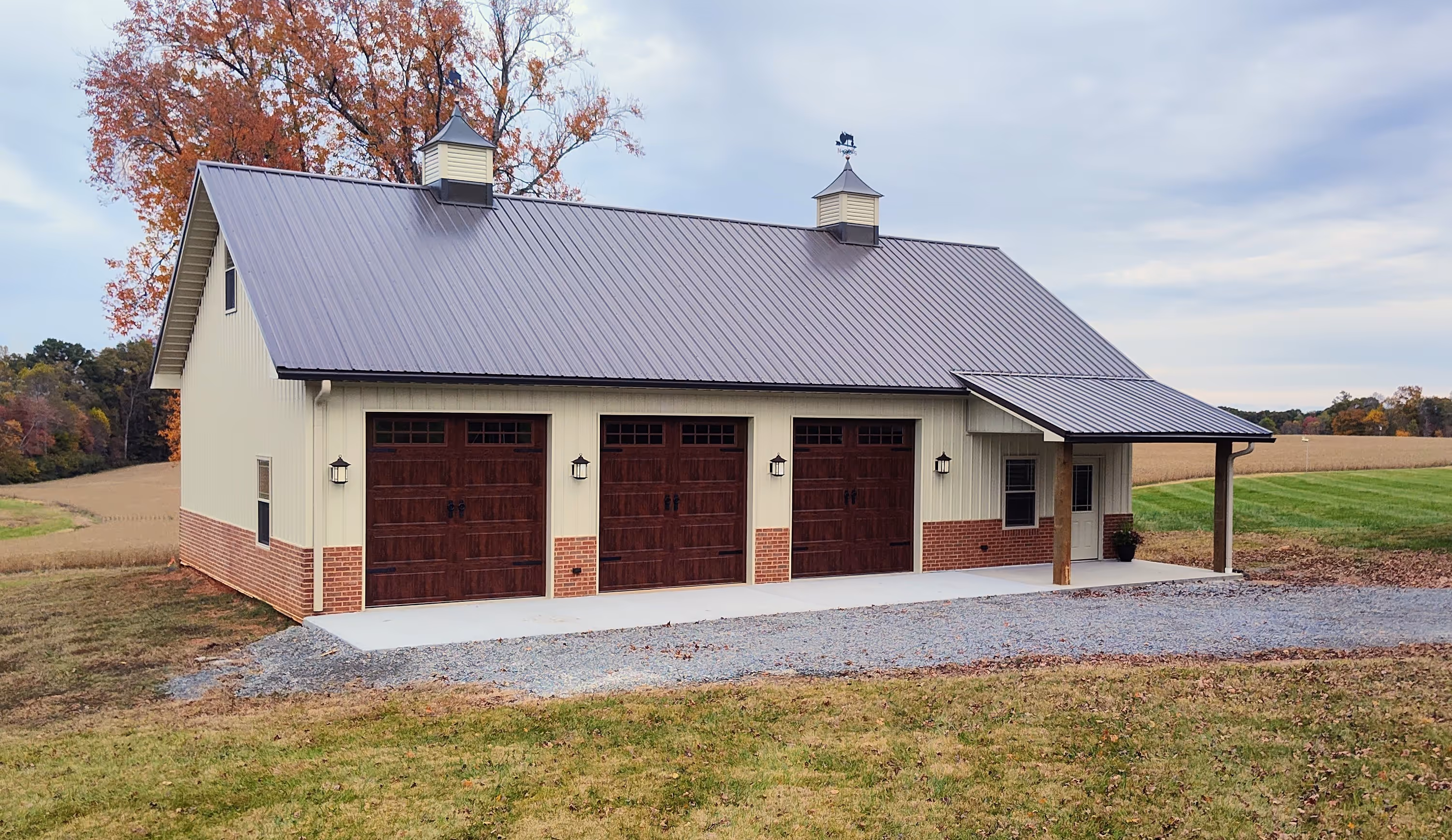 Custom post-frame building built by Carolina Custom Barns with three garage bays and a small porch