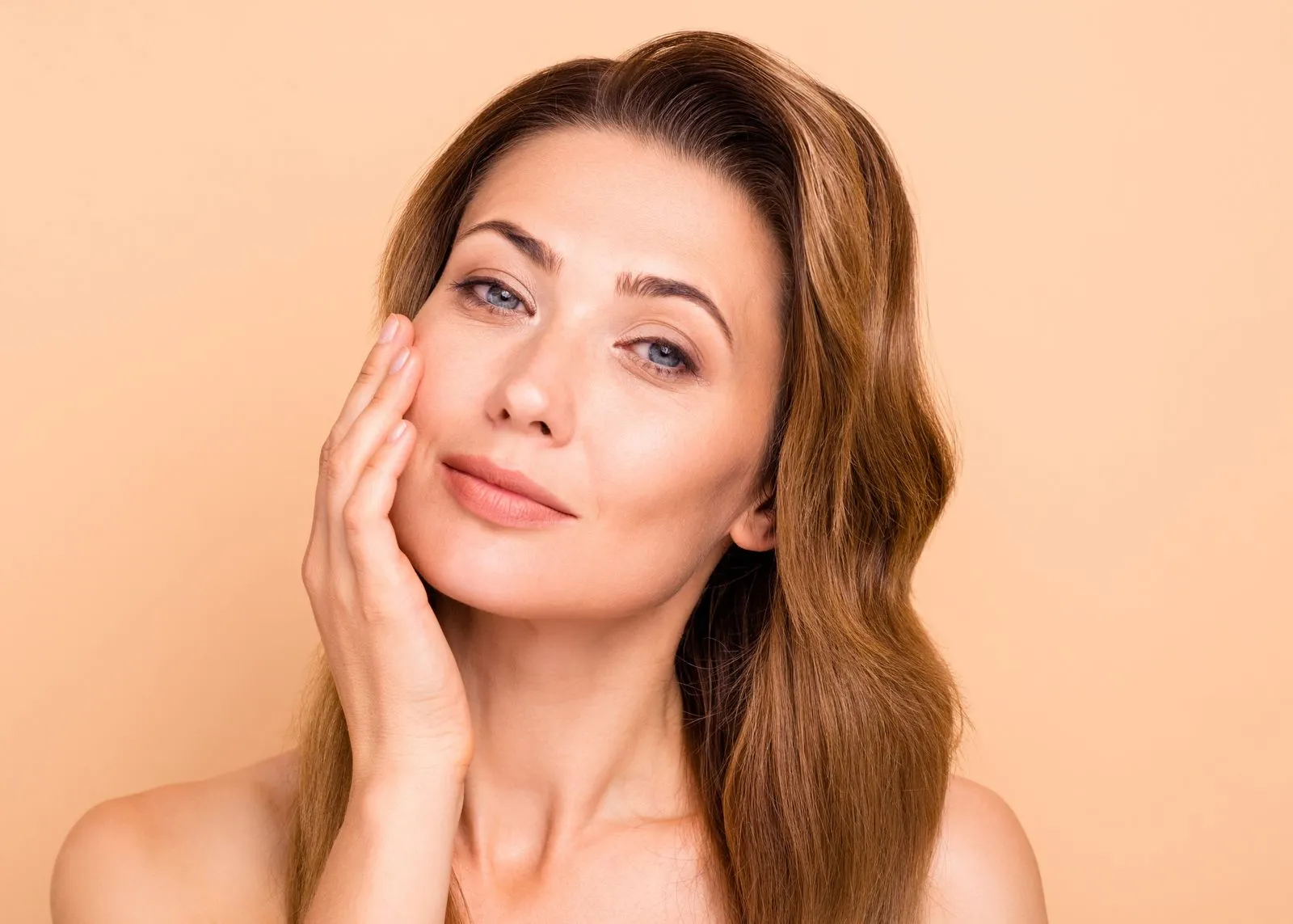A woman smiling touching her face