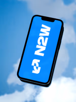 Smartphone displaying distorted white text on a blue background against a sky with clouds.