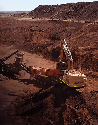 Large excavator digging in an open-pit mine with a rocky and barren landscape surrounding it.