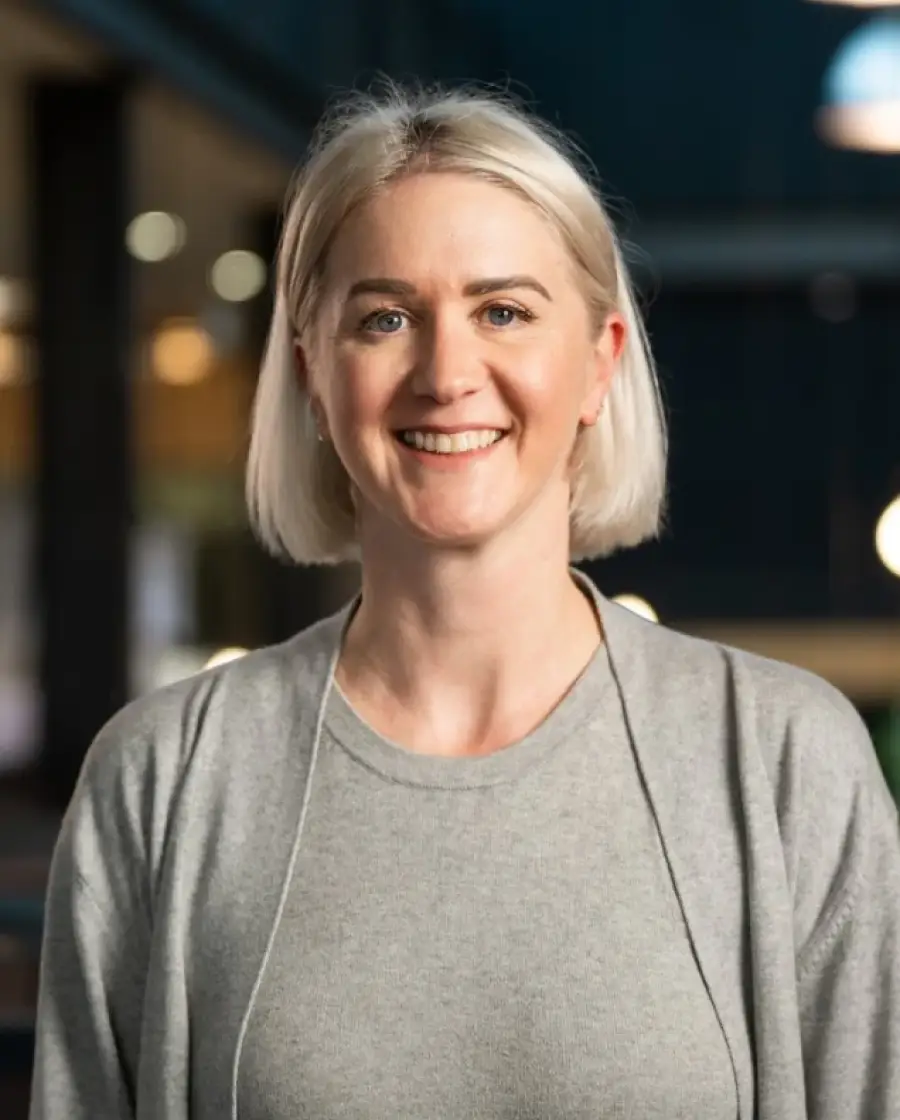 Andrea Quinn — a woman with blonde bobbed hair and fair skin, wearing a light grey sweater.