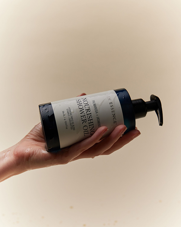 Hand holding a bottle of shower oil 