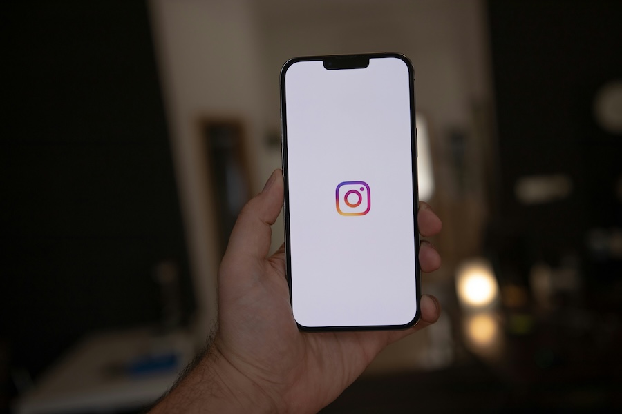 Photo of a hand holding up an iPhone with the Instagram app open