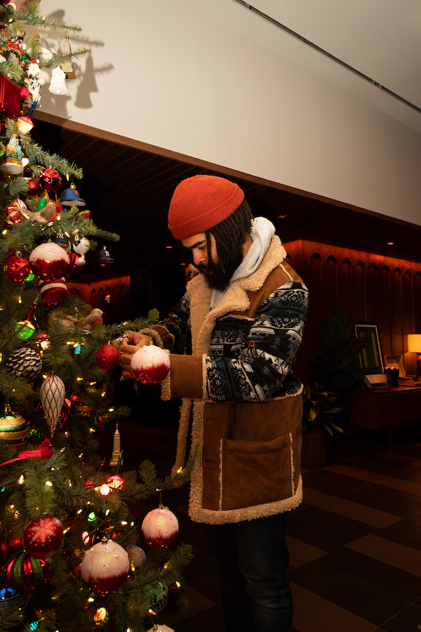 Photograph of a man hanging up ornaments on a christmas tree