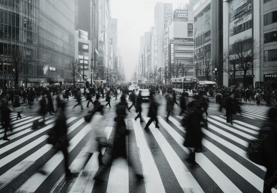 Crowded city crosswalk with blurred pedestrians walking during daytime in a busy urban area.