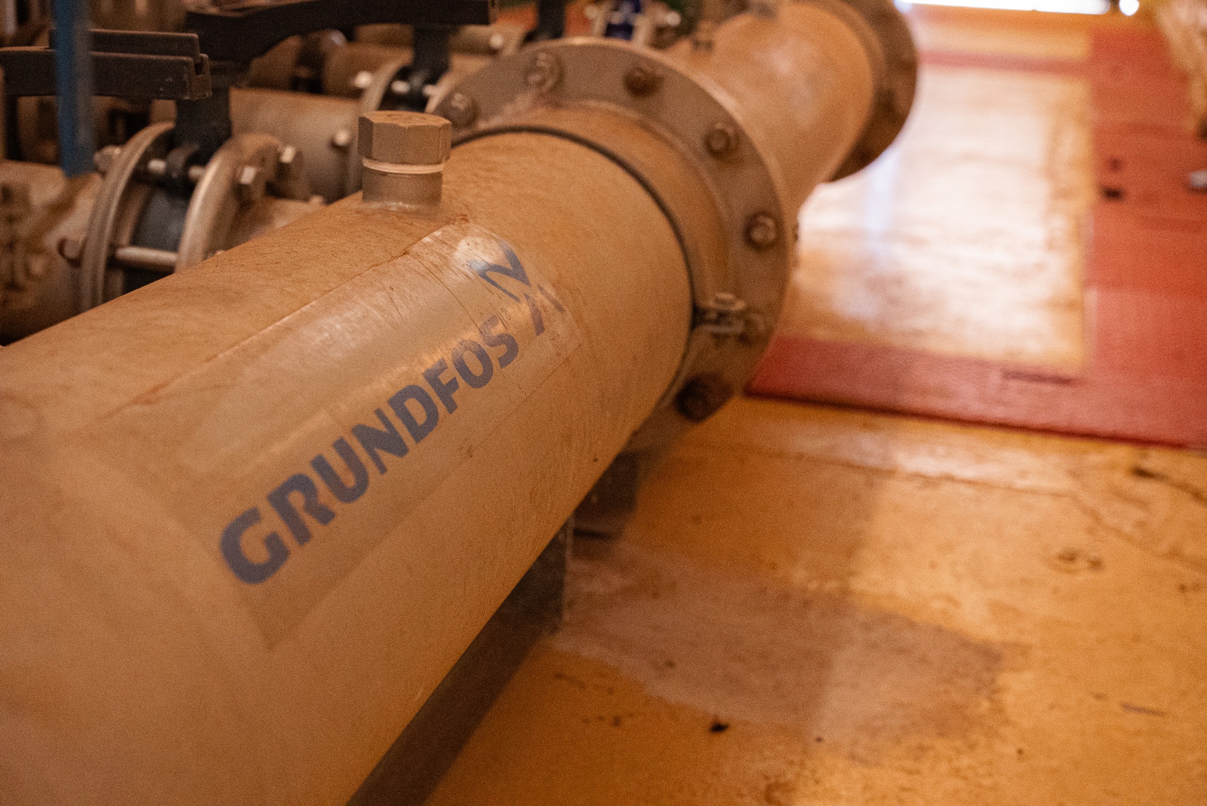 Close-up of a large industrial pipe with the brand name 'GRUNDFOS' printed on it.
