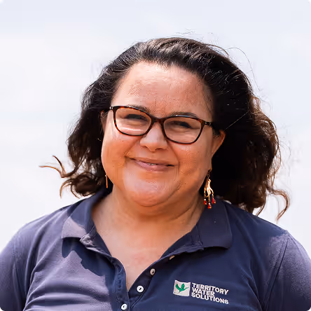 Smiling woman with glasses and wavy hair wearing a navy polo shirt with Territory Water Solutions logo.