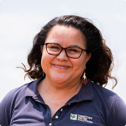 Smiling woman with glasses and wavy hair wearing a navy polo shirt with Territory Water Solutions logo.