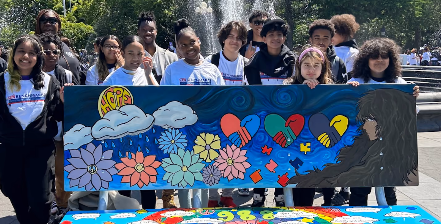 Students displaying a colorful Hope-themed bench mural at an outdoor exhibition