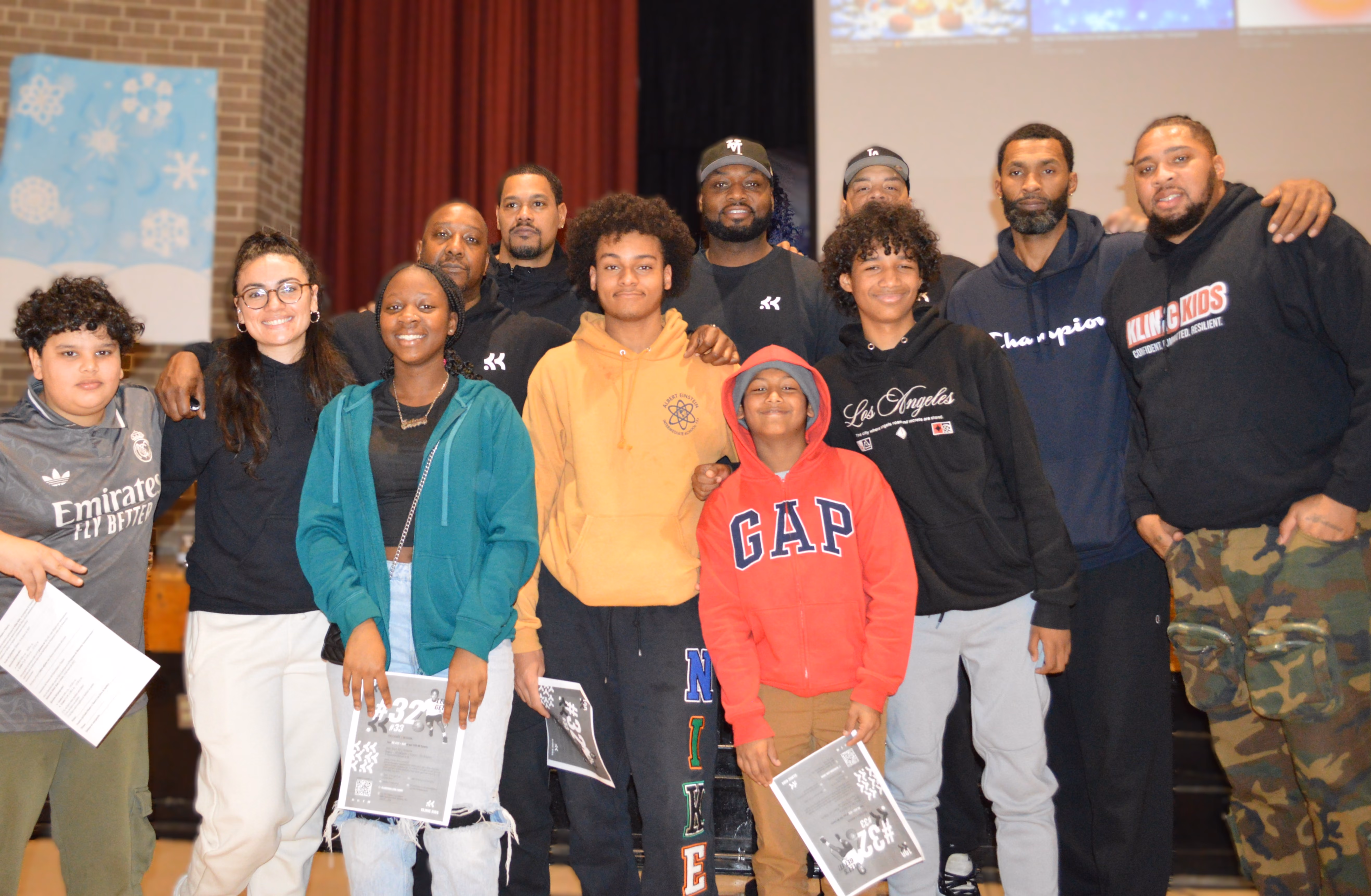 Students and adult mentors pose together holding certificates at school event