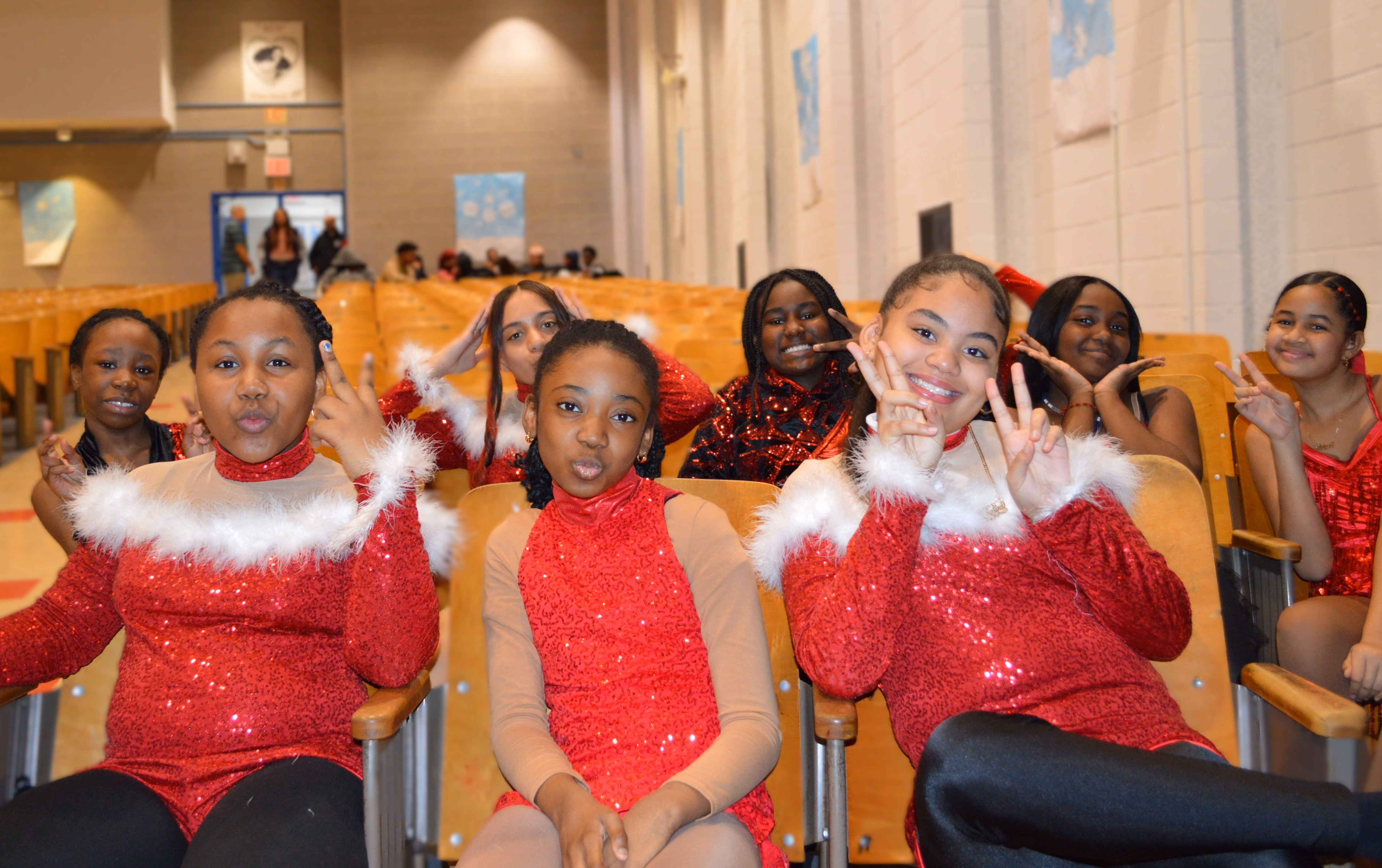 Students in red holiday performance costumes posing in auditorium seats