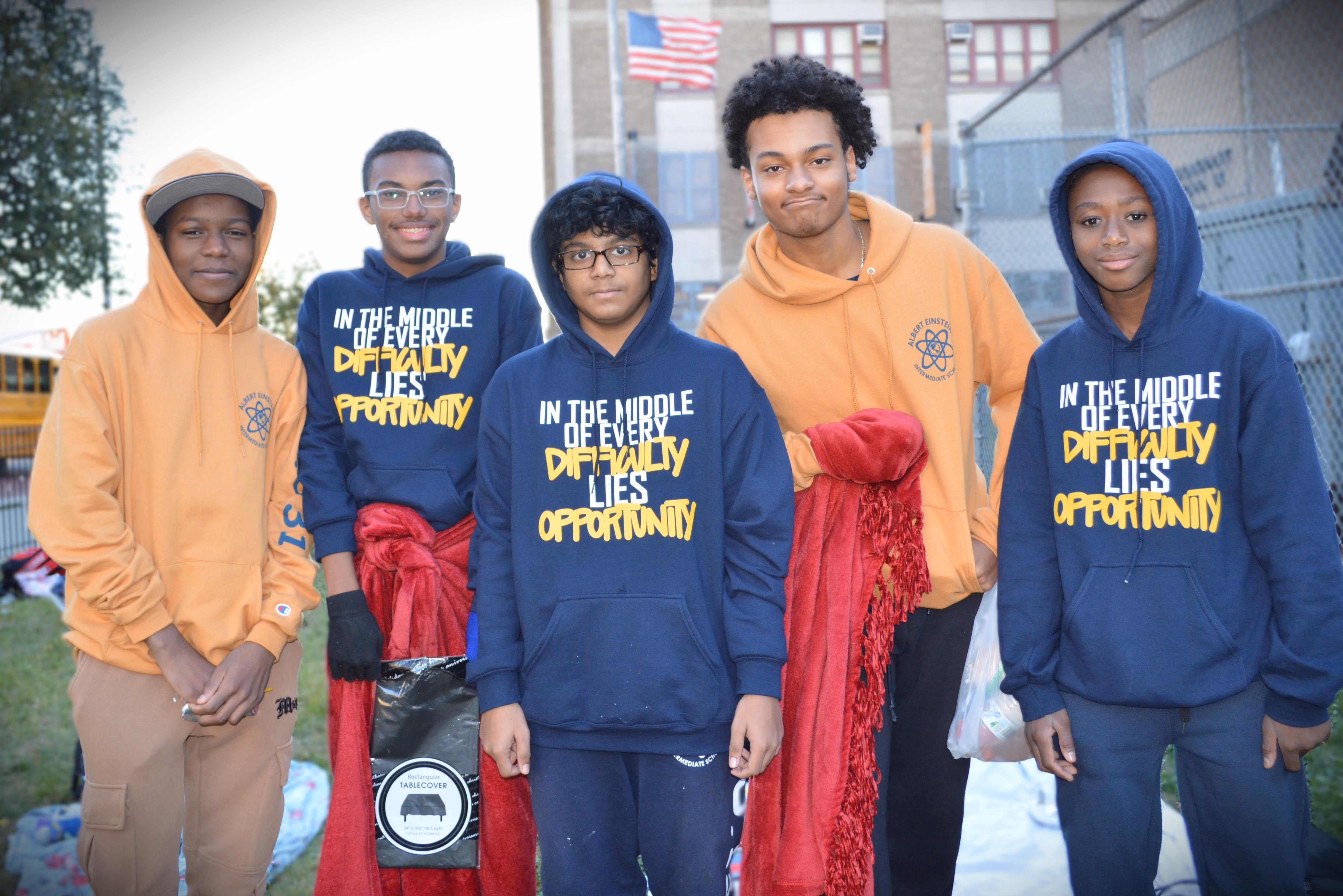 Five IS 131 students posing outdoors in school hoodies