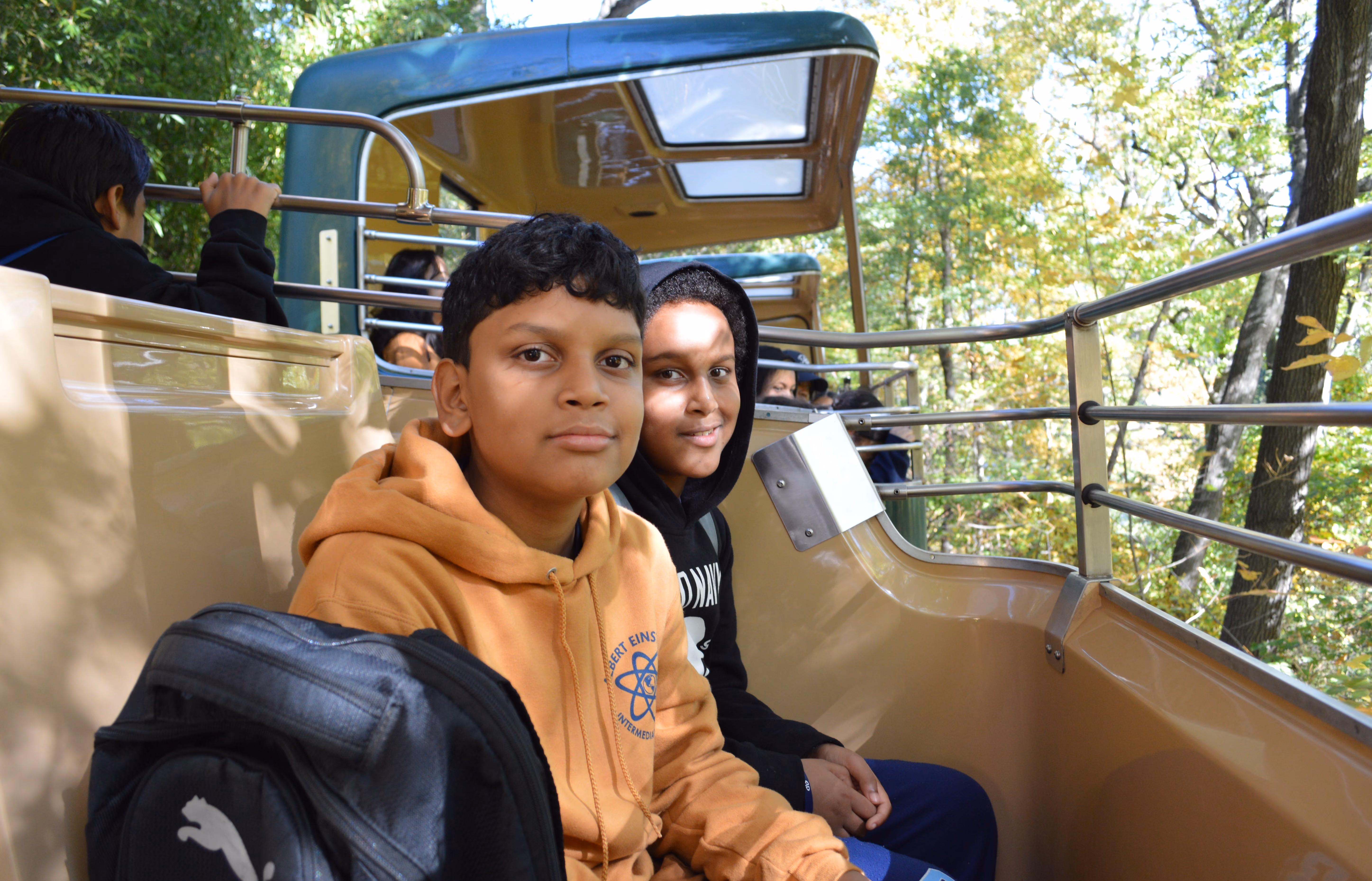 Two students riding an open-air tram on a school field trip