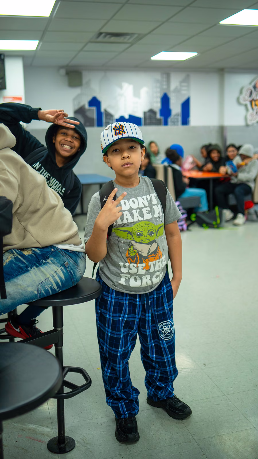 Student in a Star Wars shirt and Yankees cap making a peace sign