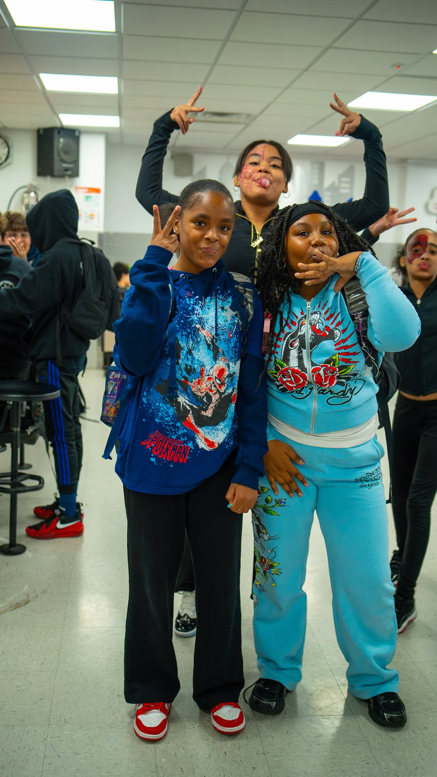 Three students posing together, one wearing a Spider-Man hoodie