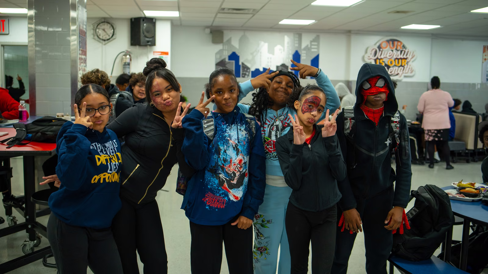 Group of students in superhero gear and face paint posing in the cafeteria