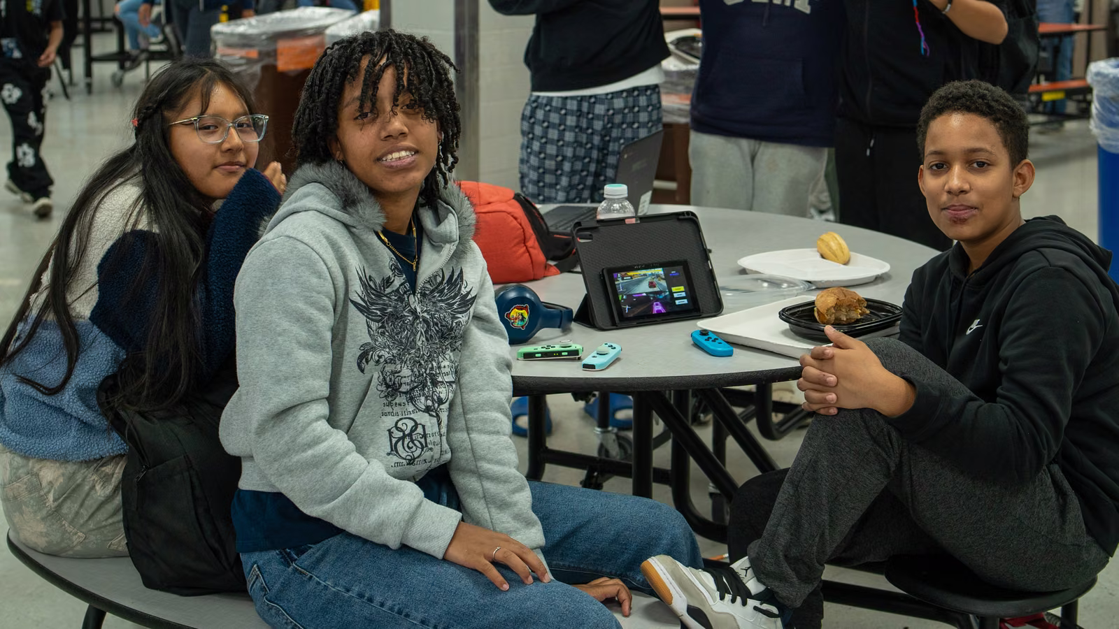 Three students sitting together at a round cafeteria table