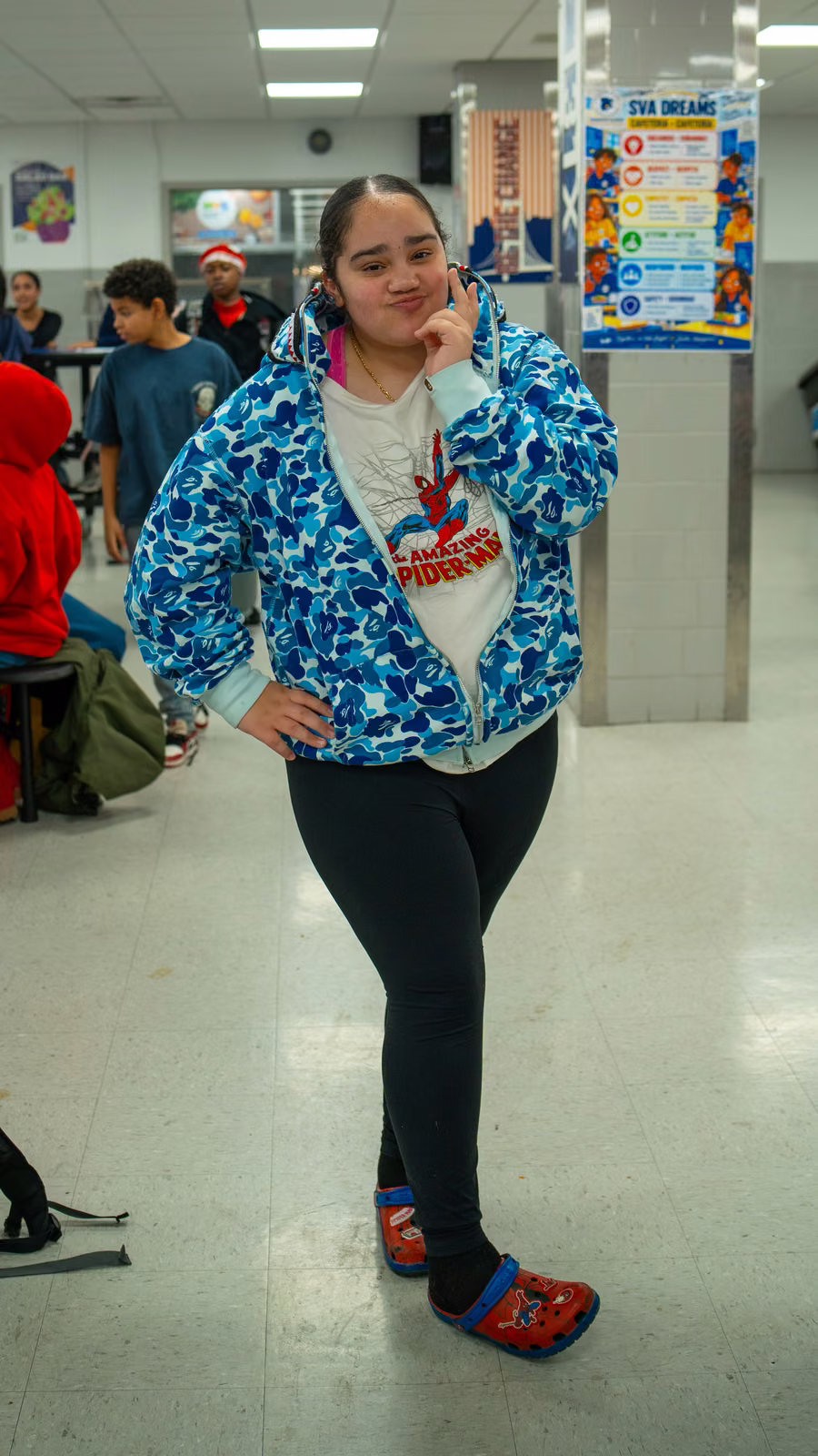 Student in a Spider-Man shirt and Spider-Man clogs posing in the cafeteria