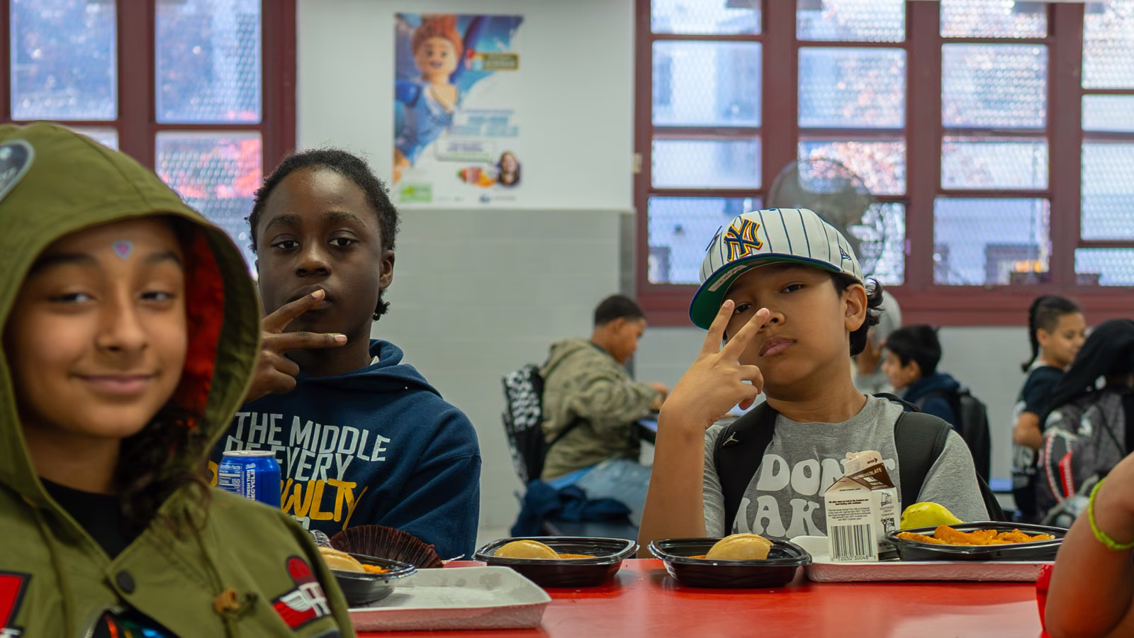 Two students making peace signs at a lunch table