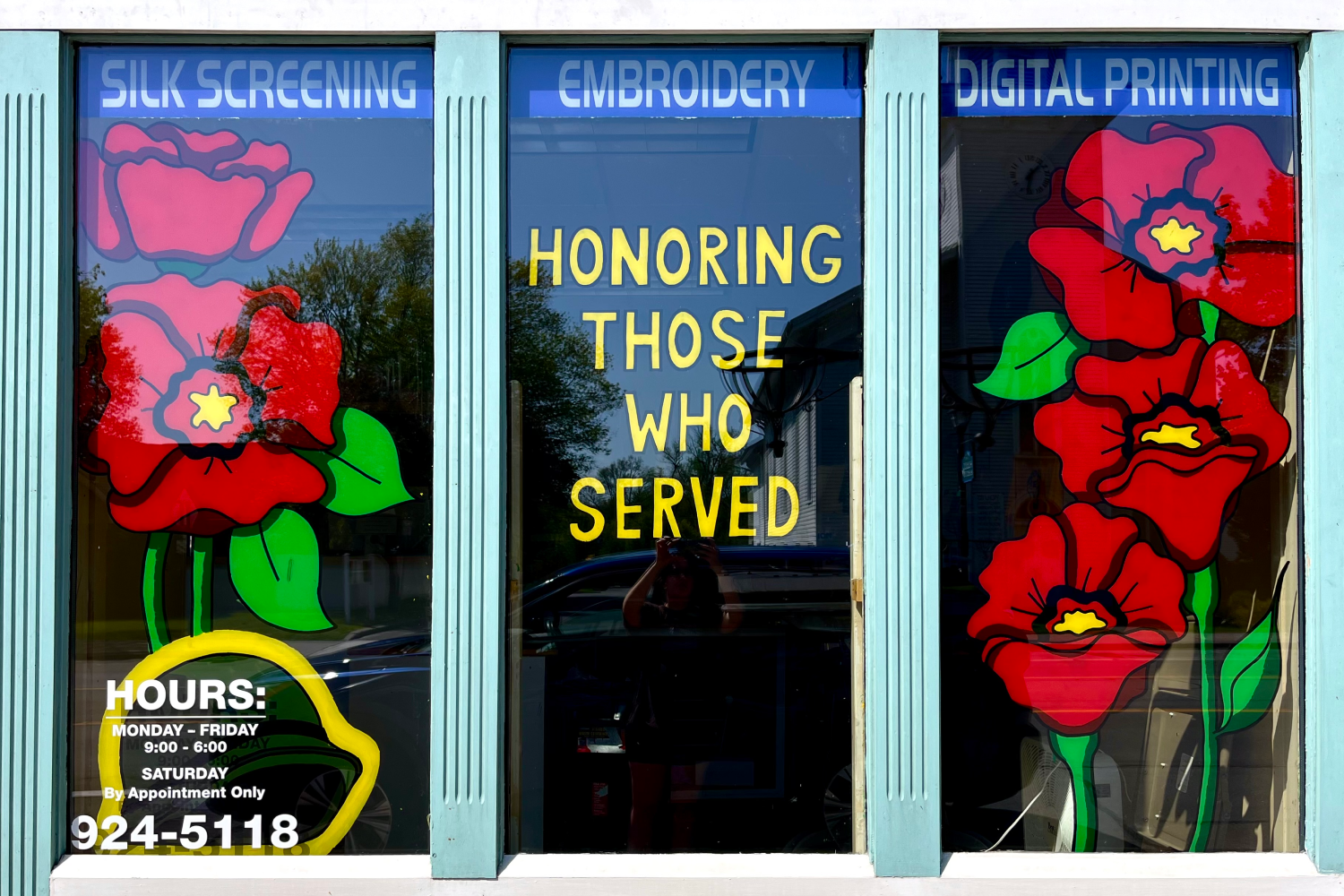 Five large red poppies with the words "Honoring those who served" in yellow letters.