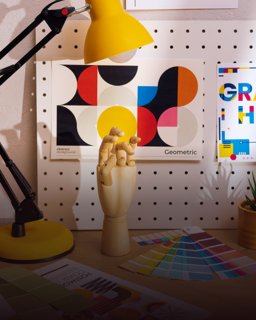 Image of a designer's desk with wooden hand model and color swatches.