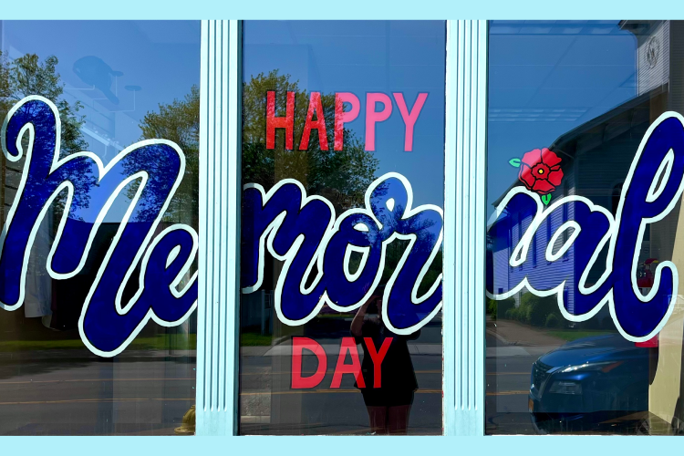 Window with a red poppy flower and the words "Happy Memorial Day" painted in blue and red cursive letters. 