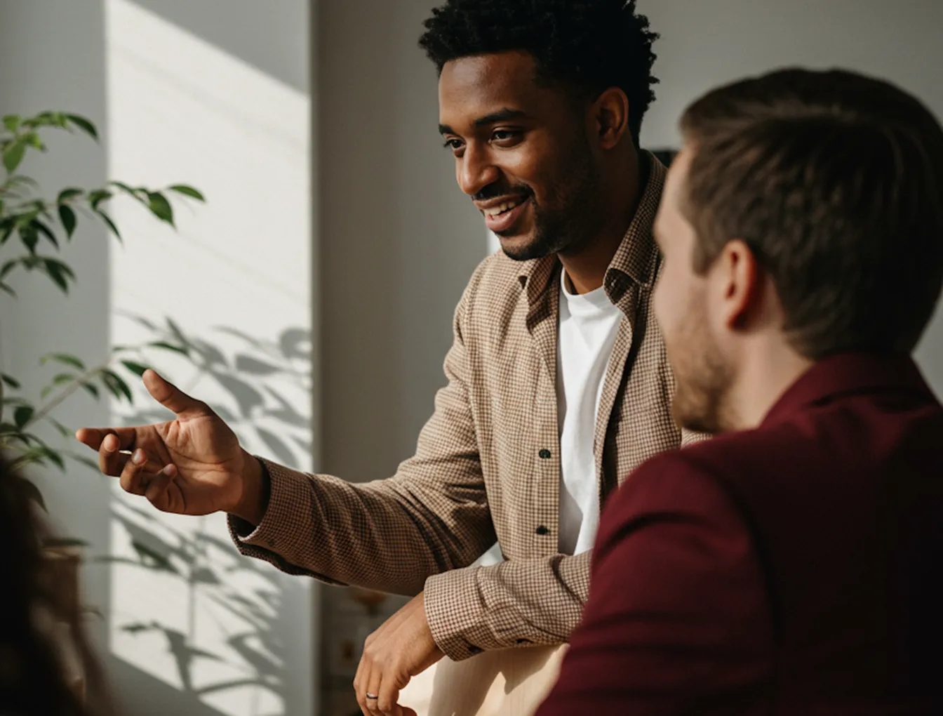 Two colleagues discussing work while sitting at a table with a laptop.