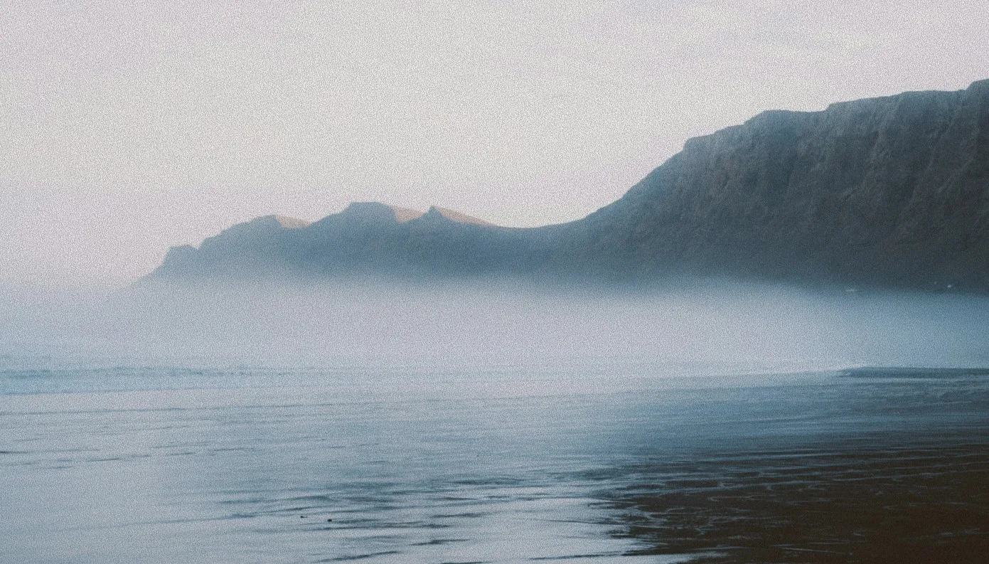 A body of water with a mountain in the background.