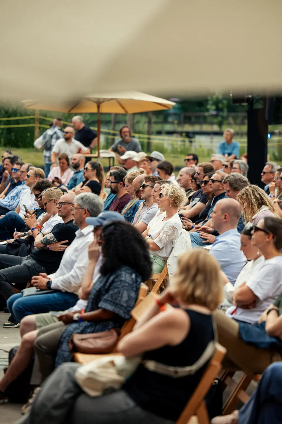 Four people sitting on grass in a park, chatting and laughing with trees and a decorative balloon structure in the background at the Love Tomorrow Summit