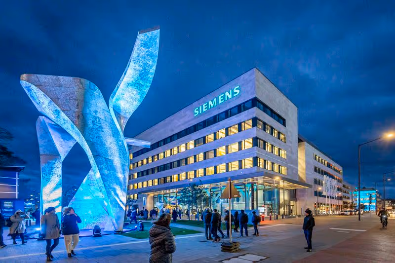 Das Siemens Gebäude mit einer Skulptur und farblich beleuchtet während des Lichterfests