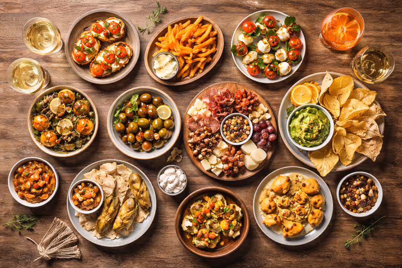 Draufsicht auf einen Tisch mit mediterranen Tapas im Patio - KI